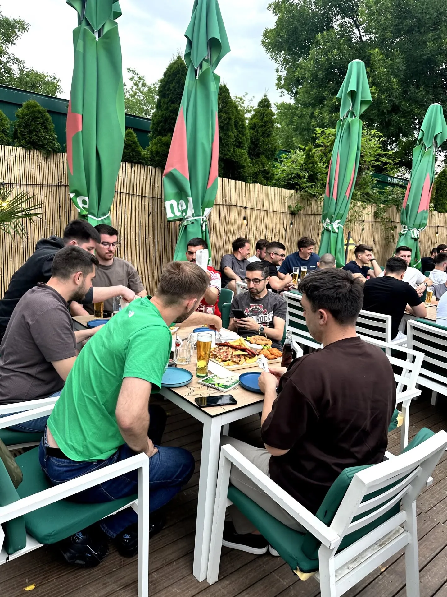 Grup de prieteni la o masă pe terasa Thalia Garden, seara, cu ghirlande luminoase și un platou de mâncare.